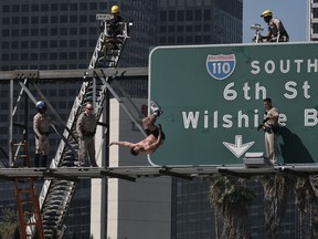 California Highway Patrol officers watch as a man jumps from a highway sign in downtown Los Angeles on Wednesday, June 27, 2018.