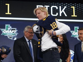 Rasmus Dahlin, of Sweden, puts on a jersey after being selected by the Buffalo Sabres during the NHL hockey draft in Dallas, Friday, June 22, 2018. (AP Photo/Michael Ainsworth)