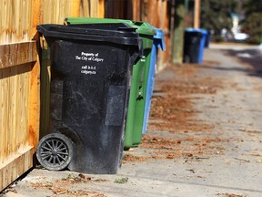 A black cart is shown with compost and recycle bins in an alley in the Elboya community in southwest Calgary on April 18, 2018.