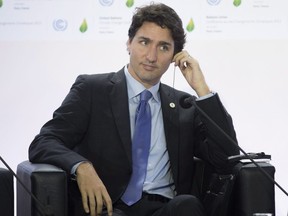 Canadian Prime Minister Justin Trudeau adjusts his translation aid as he listens to speakers during a session on carbon pricing at the United Nations climate change summit in Le Bourget, France, on Nov. 30, 2015.