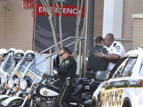 A Orange County Sheriff Motor deputy,center, gives support to a Orlando Police Motor officer,right, at Orlando Regional Medical Center after a OPD officer was shot and severely injured while responding over night to a domestic dispute call Monday, June 10, 2018.
