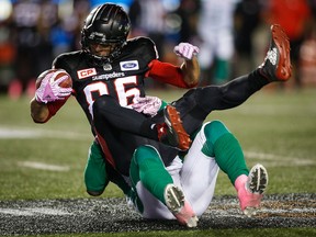 In this Oct. 20, 2017, file photo, Saskatchewan Roughriders' Samuel Eguavoen, bottom, tackles Calgary Stampeders' Anthony Parker during first half CFL football action in Calgary.