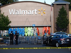 Police investigate the scene of a shooting at a Walmart in Tumwater, Wash., Sunday, June 17, 2018. A gunman injured a teen and shot a man in a pair of carjacking attempts Sunday, before being killed by a bystander outside a Washington state Walmart store.