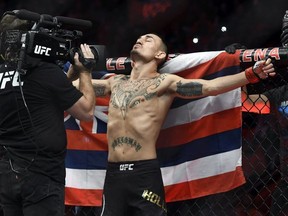 Max Holloway, stands in front of the state flag of Hawaii, as he prepares to fight Jose Aldo of Brazil during a UFC 218 featherweight mixed martial arts bout, Sunday, Dec. 3, 2017, in Detroit.
