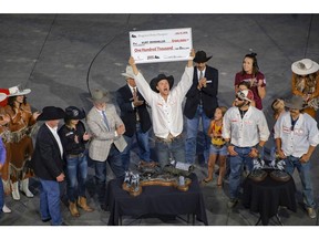 Kurt Bensmiller , surrounded by dignitaries, family and outriders, holds up his cheque after winning the championship round of the Rangeland Derby at the Calgary Stampede in Calgary, Ab., on Sunday July 15, 2018. Mike Drew/Postmedia