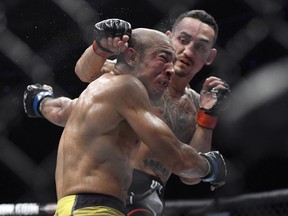Max Holloway, right, punches Jose Aldo, of Brazil, during the third round of a UFC 218 featherweight mixed martial arts bout, early Sunday, Dec. 3, 2017, in Detroit. Holloway defeated Aldo by third-round TKO.