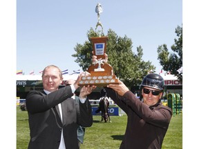 Kevin Burgenmeister (L) Director Thermal Operations, Electric Generation, ATCO joins winner Eric Lamaze (CAN) in hoisting the ATCO Cup at the Spruce Meadows North American in Calgary, AB on Thursday, July 5, 2018. Lamaze won in a jump-off. Jim Wells/Postmedia