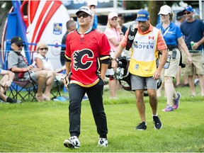 Ryan Yip, of Calgary, puts on a Calgary Flames jersey on after teeing off on the seventh hole during the final round of the Canadian Open at the Glen Abbey Golf Club in Oakville, Ont., Sunday, July 29, 2018.