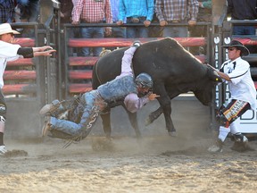 Jared Parsonage from Maple Creek Sask. can't get un-hinged from the bull named Pacesetter at the Ranchman's Renegades Smithbuilt PBR Bulbustin at the Ranchmans in SW Calgary, Alta. on Wednesday July 2, 2014. Stuart Dryden/Calgary Sun/QMI Agency