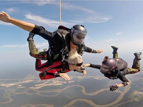 Postmedia Edmonton city editor Nicole Bergot takes part in a tandem skydive jump with Capt. John Hart of the Canadian Forces Parachute Team, the SkyHawks, at the Whitecourt Airport on Friday, July 27, 2018. Also pictured is Leading Seaman Jennifer MacKinnon, right. (Screenshot)