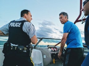 Keith Crone driving his boat with the RCMP officer that first arrived on scene to help people whose boat capsized in the icy waters of Ghost Lake Reservoir Saturday night. (Supplied)