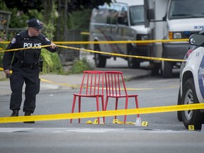 A police officer passes chairs marking evidence at the scene where a gunman shot more than a dozen people on Danforth Avenue in Toronto the night before on July 22, 2018.
