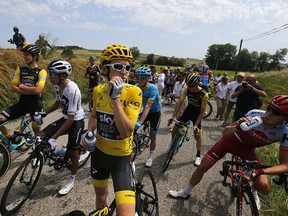 Riders with Britain's Geraint Thomas, wearing the overall leader's yellow jersey Britain's wait on the road after a farmer's protest interrupted the 16th stage of the Tour de France, Tuesday, July 24, 2018.