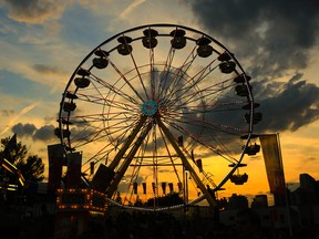 The sun sets behind the big ferris wheel on the Calgary Stampede midway, Wednesday July 12, 2017.