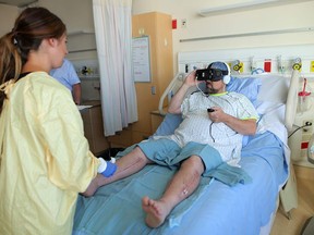 Jaclyn Frank, wound care physiotherapist bandages patient Graydon Cuthbertson's wounds as he wears a Samsung Gear virtual reality headset while being treated at the Rockyview Hospital in Calgary, on Thursday August 30, 2018.