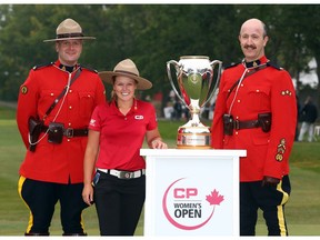 REGINA, CANADA - AUGUST 26:  Brooke Henderson of Canada with the champions trophy and Canadian Mounties following the final round of the CP Women's Open at the Wascana Country Club on August 26, 2018 in Regina, Canada.