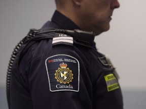 A Canadian Border Services agent stands watch at Pearson International Airport in Toronto, Ont. on Tuesday, December 8, 2015. Canada's border agency plans to compare images of people arriving in the country with photographs of suspects on watchlists to keep out alleged terrorists and other criminals. THE CANADIAN PRESS/Darren Calabrese