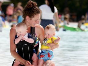 Mom, Allison Ashkin with twins, Atticus and Arlee, 6months, cools down at the Bowness Park Wading pool as the heat wave continues in Calgary on Thursday August 9, 2018.