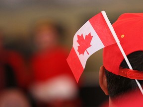 A new Canadian wears a flag on his hat after receiving Canadian citizenship in a Canada Day ceremony at Heritage Park.