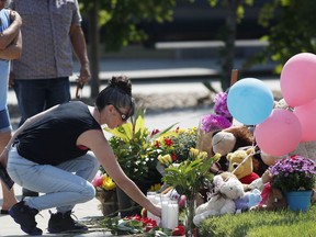 Irene Montoya of Aurora, Colo., places a bouquet of flowers as tributes grow outside the home where a pregnant woman and her two daughters lived Thursday, Aug. 16, 2018, in Frederick, Colo.