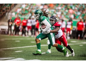 Saskatchewan Roughriders running back Tre Mason (10) runs the ball under pressure from the Calgary Stampeders defence during first half CFL action in Regina on Sunday, August 19, 2018.