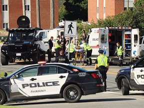 Police officers and paramedics survey the area of a shooting in Fredericton, N.B., on Friday, Aug. 10, 2018.