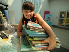 Adelaide Longfield, 7, checks out a stack of books at Nose Hill Library in Calgary, on Thursday August 16, 2018 in advance of Saturday's Calgary Public Library's event Love Your Library Day. Leah Hennel/Postmedia