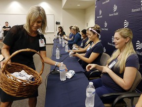 Banner Desert Medical Center CEO Laura Robertson, left, hands out baby outfits Friday, Aug. 17, 2018, in Mesa, Ariz., to the sixteen pregnant nurses who work together in the intensive care unit. (AP Photo/Ross D. Franklin)