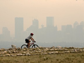 Bill McCool rides on Nose Hill with Calgary's smokey skyline as a backdrop on Sunday afternoon, August 19, 2018. Several weekend outdoor athletic events were cancelled due to the continued heavy forest fire smoke from B.C. Gavin Young/Postmedia