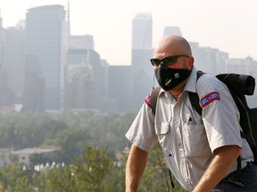 Jerry Hoult from Canada Post rides by the smokey cityscape on Crescent Hill as smoke has thickened in Calgary on Wednesday August 8, 2018. Darren Makowichuk/Postmedia
