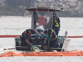 A spill response team works at the scene where a tugboat capsized and sank on the Fraser River between Vancouver and Richmond, B.C., on Tuesday, Aug. 14, 2018. Four people aboard the vessel were all rescued.
