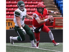 Calgary, AB - September 29, 2018. University of Calgary quarterback #12 Adam Sinagra escapes pressure from University of Saskatchewan Huskies # 91 Riley Pickett. The  Dinos defeated the Huskies 33-13 Saturday afternoon at McMahon Stadium during Canada West football action.  Photo by David Moll / Dinos Digital Media