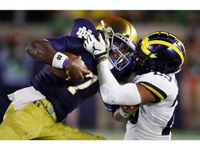 SOUTH BEND, IN - SEPTEMBER 01:  Brandon Wimbush #7 of the Notre Dame Fighting Irish tries to avoid the tackle of Tyree Kinnel #23 of the Michigan Wolverines at Notre Dame Stadium on September 1, 2018 in South Bend, Indiana.