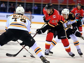 Calgary Flames' Sean Monahan (C in red) fights for the puck with Boston Bruins' Charlie McAvoy (L) during their 2018 NHL China Games match in Shenzhen in China's southern Guangdong province on September 15, 2018. (Photo by STR / AFP) / China OUTSTR/AFP/Getty Images