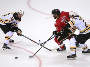 Matt Grzelcyk, left, and Jakob Forsbacka Karlsson of the Boston Bruins and TJ Brodie of the Calgary Flames battle for the puck during their game in the 2018 NHL China Games in Shenzhen Saturday, Sept. 15, 2018. (Color China Photo via AP)