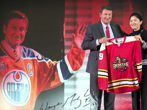 Former NHL hockey player Wayne Gretzky, left, is presented with a Beijing Kunlun Red Star hockey jersey with his name and number during a promotional event in his role as global ambassador for the team, part of the Russia-based Kontinental Hockey League, in Beijing, Thursday, Sept. 13, 2018. Gretzky says the NHL should again allow its players to compete in the Winter Olympics because sending the world's top hockey players is "always much better for everyone."
