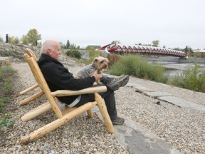 Walter Wiens relaxes with his dog Harley in the newly opened park area in West Eau Claire Park in Calgary on Friday, September 21, 2018. Wiens lives in Sunnyside, just on the other side of the Peace Bridge in the background. Jim Wells/Postmedia