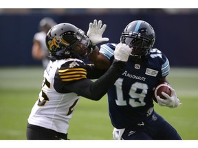 Toronto Argonauts wide receiver S.J. Green (19) hits Hamilton Tiger-Cats defensive back Terrence Frederick (25) with a stiff arm as he runs up field with the ball during second half CFL football action, in Toronto, Saturday, Sept. 8, 2018.