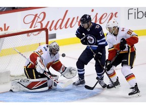 Calgary Flames' goaltender Jeff Glass (31) tries to stop the bouncing puck with Winnipeg Jets' Nikolaj Ehlers (27) battling Ryan Sproul (96) in front of the net during third period pre-season NHL hockey action in Winnipeg, Friday, September 21, 2018.
