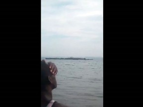 This framegrab taken from mobile phone footage shows a person on the shore watching the search and rescue of people standing on the capsized hull of a ferry, on Lake Victoria, Tanzania. The death toll rose above 100 on Friday Sept. 21, 2018, after the ferry capsized and sank on Lake Victoria, Tanzania state radio reported.