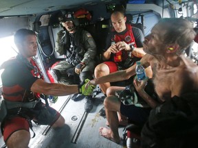 Willie Schubert of Pollocksville, N.C., right, shakes the hand of U.S. Coast Guard rescue swimmer Samuel Knoeppel, left, as flight mechanic, David Franklin, second from left, and swimmer Randy Haba, second from right, stow their gear after Schubert was rescued off a stranded van in Pollocksville on Monday, Sept. 17, 2018.