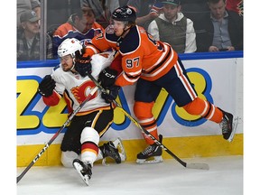 Edmonton Oilers superstar Connor McDavid hits the Calgary Flames' Rasmus Andersson into the boards during pre-season NHL action at Rogers Place in Edmonton on Saturday. Photo by Ed Kaiser/Postmedia.