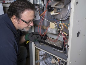 Technician looking over a gas furnace with a flashlight before cleaning it.