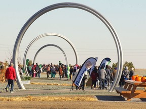 Visitors arrive uner three of five rings at the entrance to the park during the official opening of Manmeet Singh Bhullar Park in northeast Calgary on Saturday, October 20, 2018. Bhullar was the first turbaned Sikh to hold a cabinet position in the provincial government. Jim Wells/Postmedia