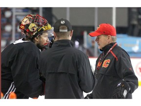 Flames head coach Bill Peters (R) talks to goalie Mike Smith and another coach during practice in Calgary on Friday. Photo by Jim Wells/Postmedia.