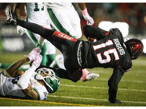 Saskatchewan Roughriders' Crezdon Butler, left, knocks Calgary Stampeders' Eric Rogers into the air during CFL football action in Calgary, Saturday, Oct. 20, 2018.