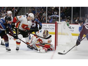Calgary Flames goaltender David Rittich (33) reaches for the puck controlled by Colorado Avalanche right wing Mikko Rantanen (96) as Avalanche left wing Gabriel Landeskog (92) attacks past Flames defenseman Juuso Valimaki (8) during the first period of an NHL hockey game Saturday, Oct. 13, 2018, in Denver.