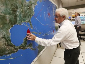 National Oceanic and Atmospheric Administration public affairs officer Dennis Feltgen updates the progress of Hurricane Michael on a large map, Tuesday, Oct. 9, 2018, at the Hurricane Center in Miami. At least 120,000 people along the Florida Panhandle were ordered to clear out Tuesday as Hurricane Michael rapidly picked up steam in the Gulf of Mexico and closed in with winds of 110 mph (175 kph) and a potential storm surge of 12 feet (3.7 meters).