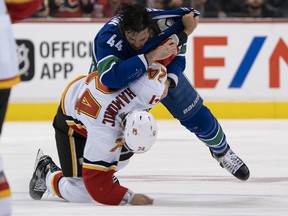 Erik Gudbranson of the Vancouver Canucks knocks down Flames defenceman Travis Hamonic on Oct. 3, 2018 at Rogers Arena in Vancouver.