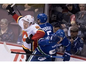 Calgary Flames centre Sam Bennett (93) fights for control of the puck with Vancouver Canucks defencemen Derrick Pouliot (5) and Troy Stecher (51) during third period NHL action at Rogers Arena in Vancouver, Wednesday, Oct, 3, 2018.
